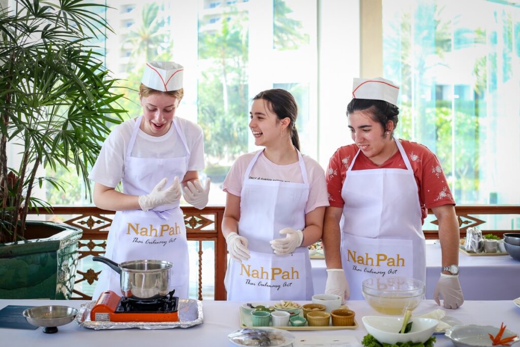 students learning how to make tom yum kung in thai cooking course